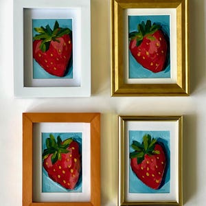 May include: Four framed paintings of red strawberries on a blue background. Each painting is in a different colored frame: white, gold, orange, and gold.