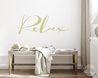 May include: A white wooden bench with a woven seat and a white throw blanket draped over it. The wall behind the bench has a gold-coloured vinyl decal that reads "Relax".