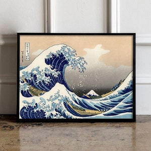 Puede incluir: Una impresión enmarcada de una xilografía japonesa que representa una gran ola rompiendo sobre un barco. La ola es azul y blanca, y el barco es pequeño y amarillo. El fondo es un cielo azul claro con nubes blancas.