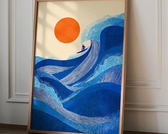 May include: Framed art print featuring a surfer riding a large blue wave under a bright orange sun. The artwork has a minimalist style with a light beige background and a wooden frame. The surfer is a small silhouette.