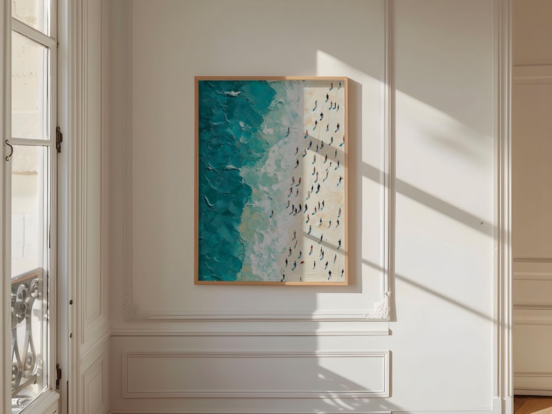 May include: A framed painting depicting an aerial view of a beach with turquoise water and white sand. The painting shows many small figures of people on the beach.
