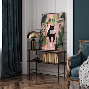 May include: A black cat sitting on a toilet reading a newspaper in a bathroom with pink walls and green plants. The cat is wearing a collar. The artwork is framed in a black frame.