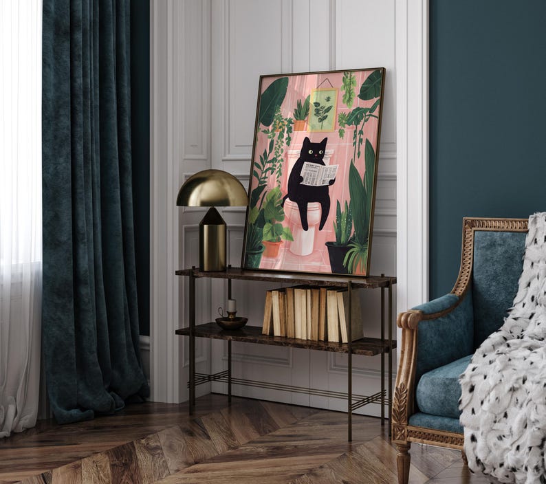 May include: A black cat sitting on a toilet reading a newspaper in a bathroom with pink walls and green plants. The cat is wearing a collar. The artwork is framed in a black frame.