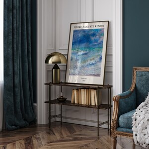 May include: A framed print of a seascape painting by Pierre-Auguste Renoir. The painting depicts a stormy sea with blue and green hues. The frame is gold and the print is titled "Seascape 1887".
