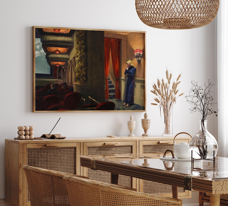 May include: A painting of a woman standing in a theater lobby, looking down at the floor. The woman is wearing a blue dress and has blonde hair. The theater lobby is dimly lit and has red velvet seats.