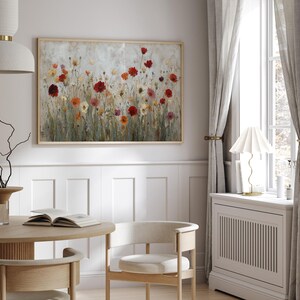 May include: A framed floral painting depicting a field of colourful flowers in shades of red, orange, and yellow. The artwork is displayed in a light-coloured room with a round wooden table, chairs, and a window with grey curtains.