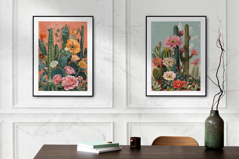 May include: Two framed prints of vintage botanical illustrations featuring cacti and flowers in shades of pink, orange, and green. The prints are set against a white wall with a vase and a wooden table in the foreground.
