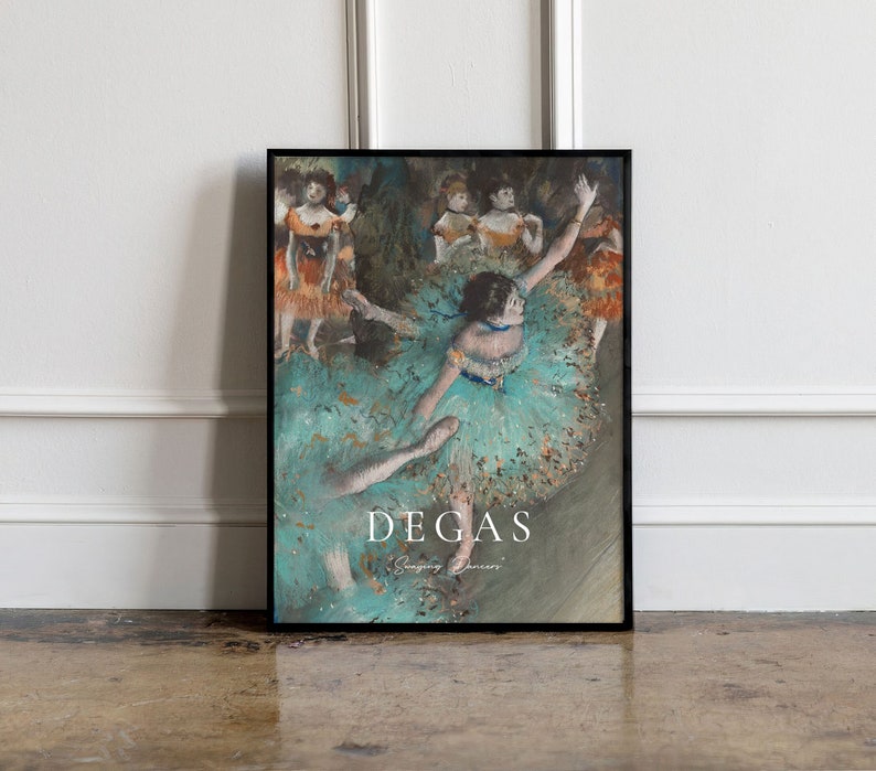 May include: A framed print of a painting by Edgar Degas, depicting a group of dancers in a ballet studio. The dancers are wearing colorful tutus and are in various poses. The painting is titled "Dancing Dancers" and is set against a light blue background.