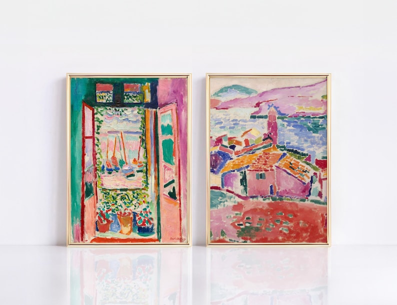 May include: Two framed paintings of colorful landscapes. The first painting shows a view from a window with a pink wall and green foliage. The second painting shows a pink house with a red roof and a blue sea in the background.