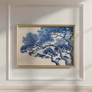 May include: A framed art print with a detailed blue and white tree illustration. The artwork is set against a cream background and enclosed in a gold-coloured frame. The image is mounted on a white wall.