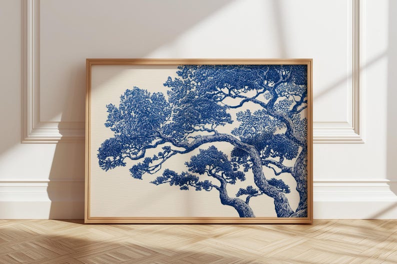 May include: A framed art print with a detailed blue and white illustration of a tree. The artwork shows a stylized depiction of a tree with intricate branches and foliage against a cream background. The frame is made of light-coloured wood.
