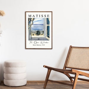 May include: A framed print of a painting by Henri Matisse titled "The Open Window". The painting depicts a view from a window overlooking a blue sea and a palm tree. The text "MATISSE" is at the top of the print, and the text "Henri Matisse, 1919" is at the bottom.