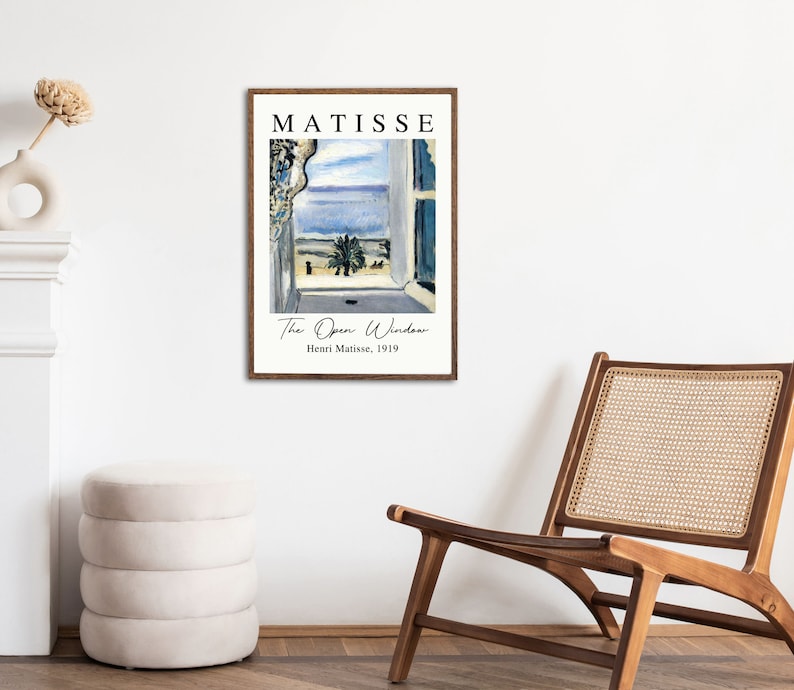 May include: A framed print of a painting by Henri Matisse titled "The Open Window". The painting depicts a view from a window overlooking a blue sea and a palm tree. The text "MATISSE" is at the top of the print, and the text "Henri Matisse, 1919" is at the bottom.