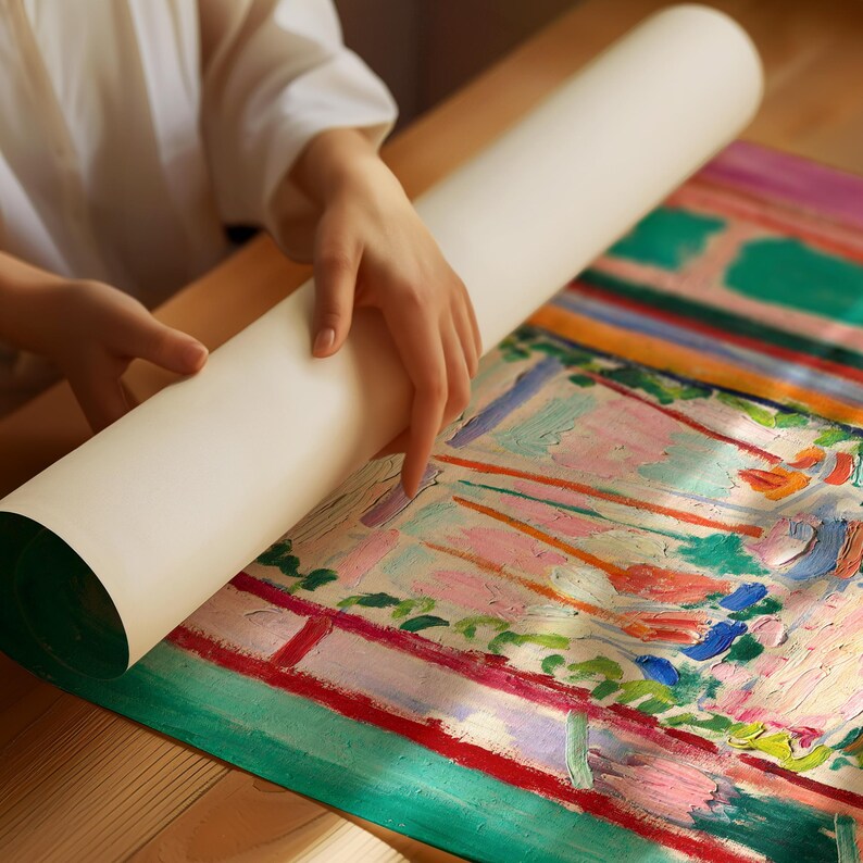May include: A person unrolling a colorful abstract painting on a wooden surface. The painting features bright colors, including green, pink, orange, and blue, and depicts a landscape scene.