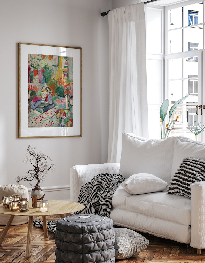 K&ouml;nnte beinhalten: Ein wei&szlig;es Sofa mit einer gestreiften Wolldecke, einem wei&szlig;en Kissen und einem schwarz-wei&szlig; gemusterten Kissen. Das Sofa steht in einem Wohnzimmer mit einem Fenster, einem Gem&auml;lde und einem Couchtisch mit einer Vase und Kerzen.