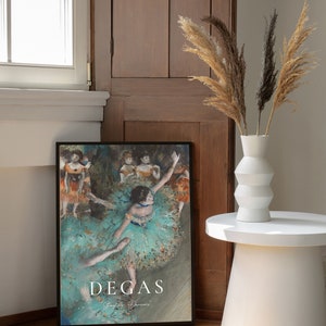 May include: A framed print of a painting by Edgar Degas depicting dancers in a turquoise and green color scheme. The title of the painting is "Dancing Dancers" and is printed in white text below the image.