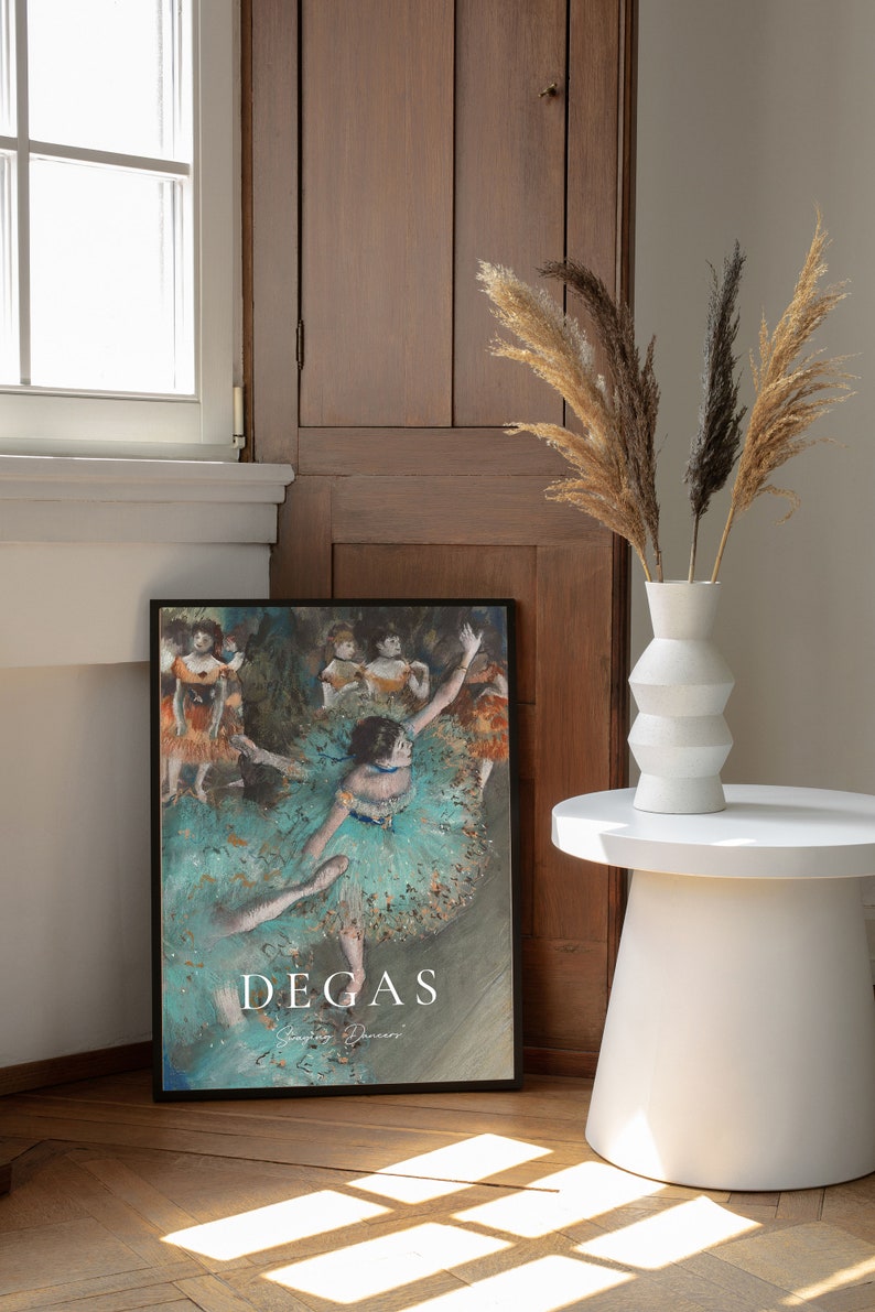 May include: A framed print of a painting by Edgar Degas depicting dancers in a turquoise and green color scheme. The title of the painting is "Dancing Dancers" and is printed in white text below the image.