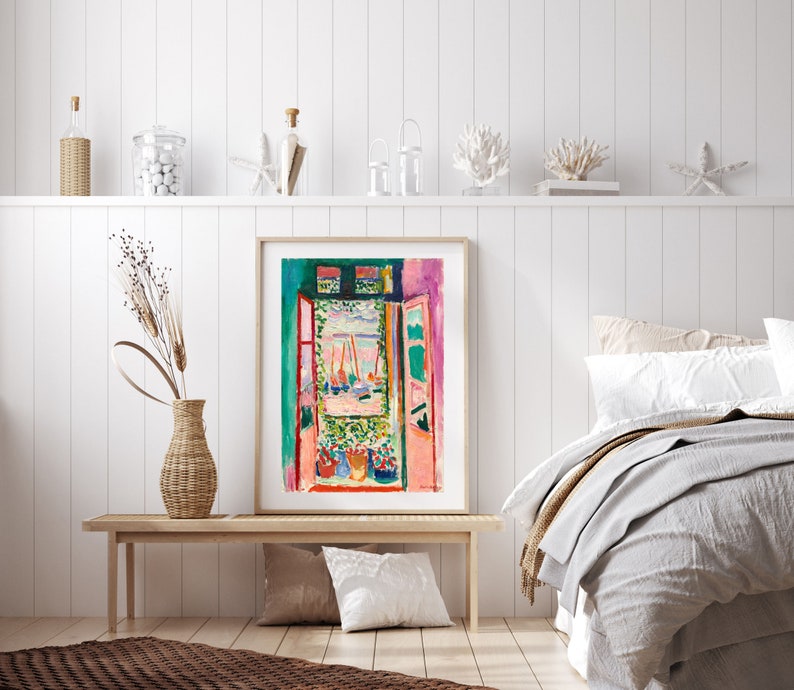 May include: A framed print of a painting depicting an open window with a view of a harbor scene. The painting is in a colorful style with shades of pink, green, blue, and yellow. The window is framed in red and the scene outside the window includes boats and a blue sky.