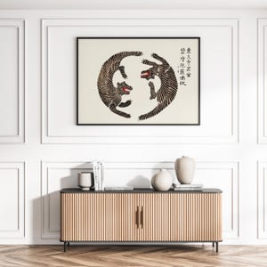 May include: A black and white illustration of two tigers facing each other in a circle. The tigers are stylized and have a geometric pattern. The background is white and the image is framed in a black frame. The text in the image reads "君子成人之美, 勿成人之恶".