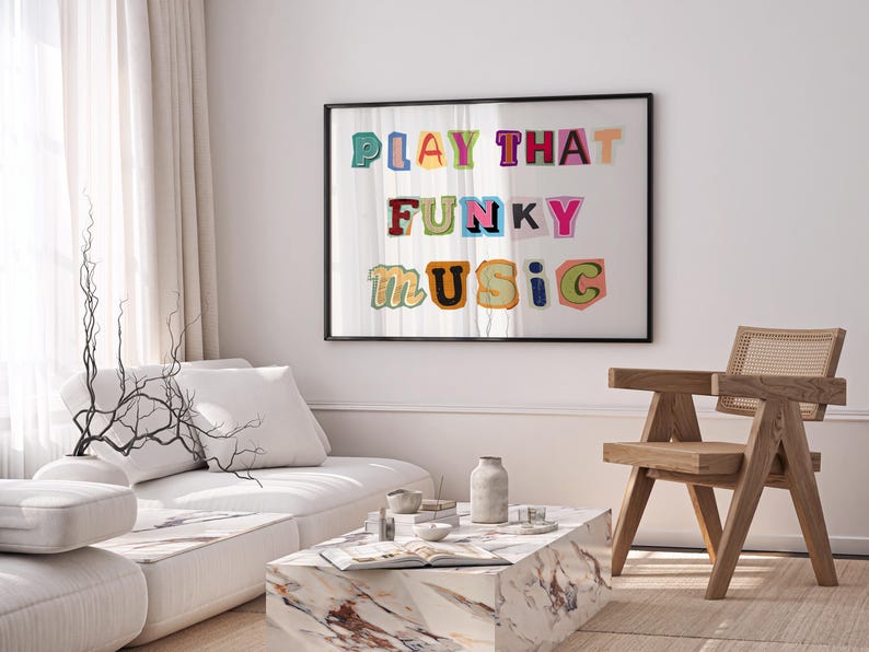 Puede incluir: Una impresi&oacute;n enmarcada con el texto "PLAY THAT FUNKY MUSIC" en letras de colores recortadas. La impresi&oacute;n est&aacute; colgada en una pared blanca sobre un sof&aacute; blanco y una silla de madera.