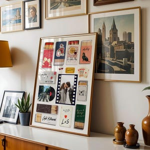 May include: A framed collage featuring various postcards, matchboxes, and a photograph. The matchboxes have colorful designs and text. The photograph shows a couple kissing. Other framed art pieces and a lamp are also visible.