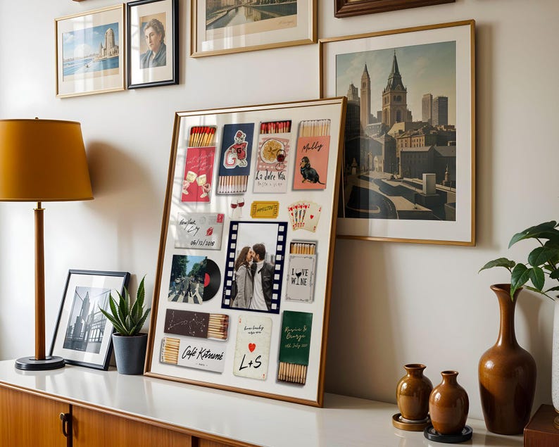 May include: A framed collage featuring various postcards, matchboxes, and a photograph. The matchboxes have colorful designs and text. The photograph shows a couple kissing. Other framed art pieces and a lamp are also visible.