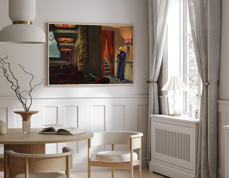 May include: A framed painting of a woman in a blue dress standing in a theater lobby. The painting is set against a white wall with white wainscoting.