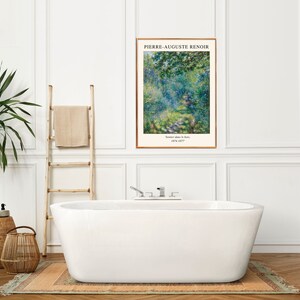 K&ouml;nnte beinhalten: Eine wei&szlig;e Badewanne mit verchromten Armaturen steht in einem Badezimmer mit wei&szlig;en W&auml;nden und T&auml;felung. Links von der Wanne steht eine Holzleiter mit einem dar&uuml;bergelegten Handtuch. An der Wand &uuml;ber der Wanne h&auml;ngt ein gerahmter Druck eines Gem&auml;ldes von Pierre-Auguste Renoir mit dem Titel "Boulevard des Italiens". Zwei Weidenk&ouml;rbe stehen auf dem Boden links von der Wanne.