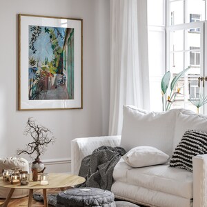 May include: A white sofa with a black and white striped throw blanket, a white pillow, and a black and white striped pillow. The sofa is in a living room with a wooden floor, a coffee table, and a framed painting of a garden scene.