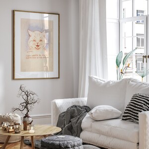 May include: A white framed print of a cartoon cat with the text "I am happy because everyone loves me". The print is hanging on a white wall in a living room with a white sofa, a throw blanket, and a coffee table with candles.