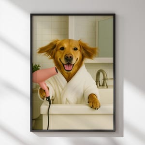 May include: Framed print featuring a Golden Retriever dog in a white bathrobe, holding a pink hairdryer. The dog is smiling with its tongue out, appearing to be in a bathroom setting. The image is framed in a black border.
