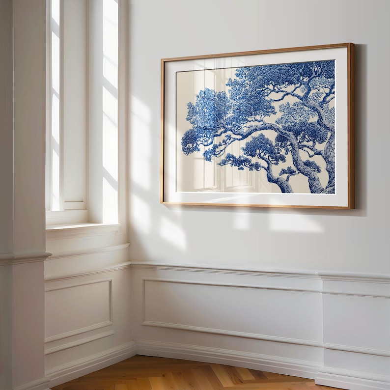 May include: A framed print displaying a detailed blue and white illustration of a tree with spreading branches. The artwork is set against a neutral background and framed in light brown wood, suitable for home decor.