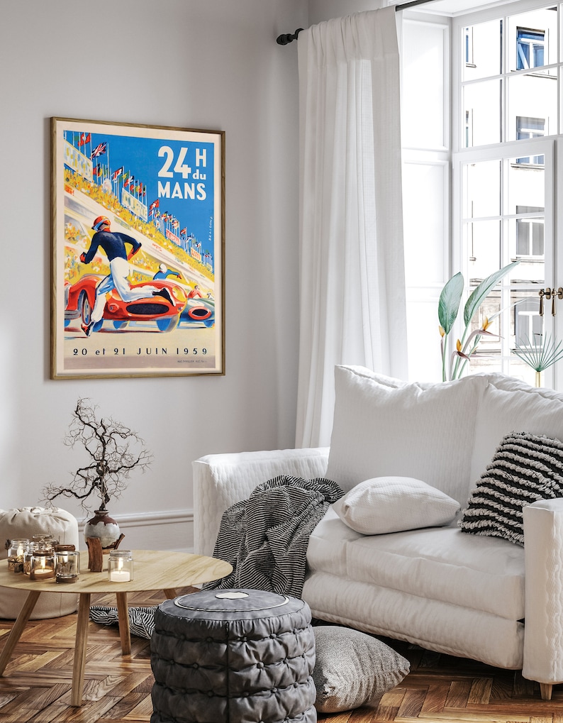 May include: A vintage poster advertising the 24 Hours of Le Mans race, featuring a red race car speeding down a track with a driver in a white racing suit. The poster is set against a blue sky with white clouds and has the text "24 H du MANS" in bold, black letters. The date "20 et 21 JUIN 1959" is printed at the bottom of the poster.