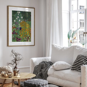 May include: A framed print of a painting depicting a field of colorful flowers in shades of orange, yellow, purple, and white. The flowers are arranged in a random pattern against a green background. The print is hanging on a white wall in a living room setting.
