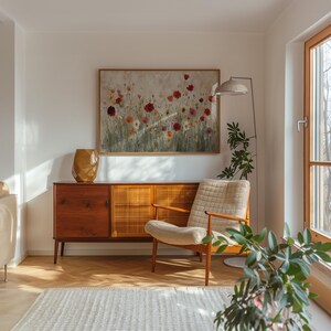 May include: A living room interior with a wooden sideboard, a beige armchair, and a framed floral artwork. A gold vase is on the sideboard. A floor lamp and a potted plant are also visible. The room has a light and airy feel.
