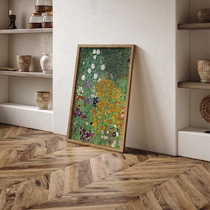 May include: A framed print of a painting depicting a field of colorful flowers. The flowers are mostly orange, yellow, and white, with some purple and blue accents. The background is a green field with a dark green forest in the distance.