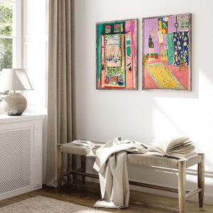 May include: Two framed paintings of a room with an open window and a view of a harbor. The paintings are in a modern style with bright colors and bold brushstrokes.