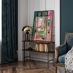 Puede incluir: Una pintura enmarcada de una ventana colorida con vista a un puerto. La ventana est&aacute; pintada en tonos de rosa, verde, azul y amarillo. La pintura est&aacute; colgada en una pared blanca en una habitaci&oacute;n con cortinas azul oscuro y un suelo de madera.