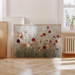 May include: A framed floral painting depicting a field of flowers in red, orange, yellow, and pink. The artwork has a neutral background and a light wooden frame. The painting is displayed in a bright room.