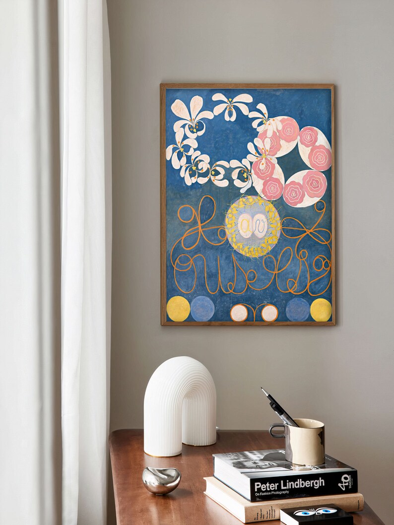 May include: A framed print of a painting with a blue background, white and pink flowers, and yellow circles. The painting is in a wooden frame.