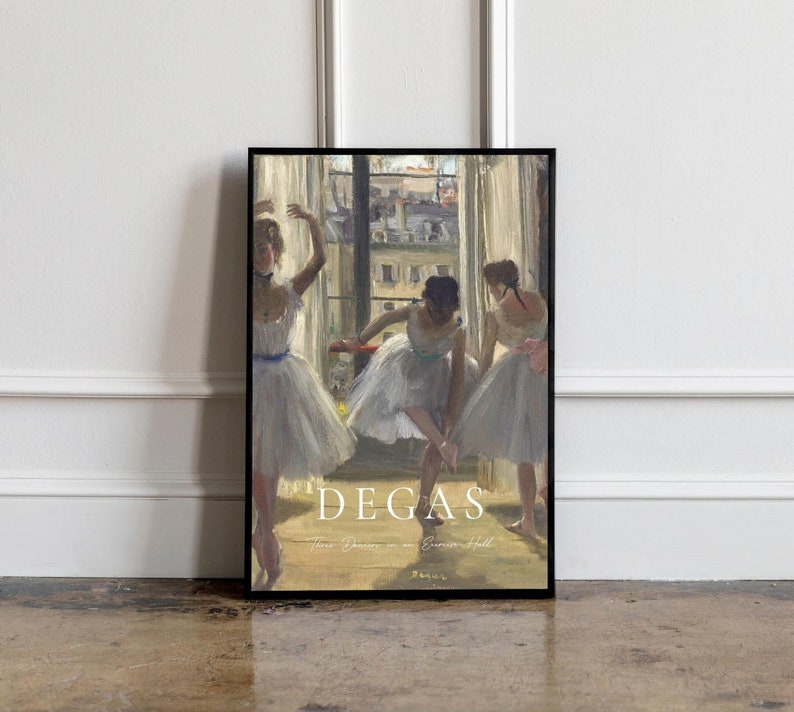 May include: A framed print of a painting by Edgar Degas titled "Three Dancers in an Exercise Hall". The painting depicts three ballerinas in white tutus practicing in a dance studio. The background features a window with a view of a city street.