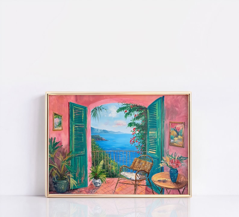 May include: A framed painting depicting a view from a balcony with open green shutters. The balcony overlooks a blue ocean with green hills in the distance. There is a chair and a table with a vase of flowers on the balcony.