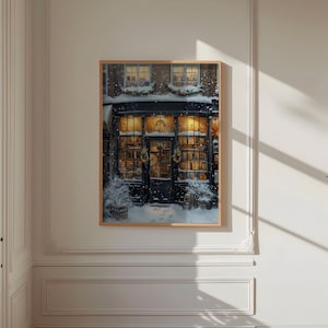 May include: A framed illustration of a storefront with a dark blue door and windows decorated with Christmas lights and wreaths. The storefront is covered in snow and the windows are filled with books.