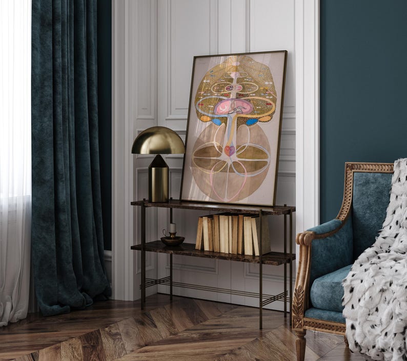 May include: A framed print of a colorful abstract design with geometric shapes and circles. The print is hanging on a wall above a shelf with books and a lamp.