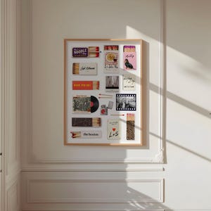 May include: A framed collection of various matchboxes, postcards, and a vinyl record. The matchboxes feature text like "NOODLE SHOP" and "BAR PRIMI". A pink matchbox has a dog illustration. The collection is displayed on a white wall.