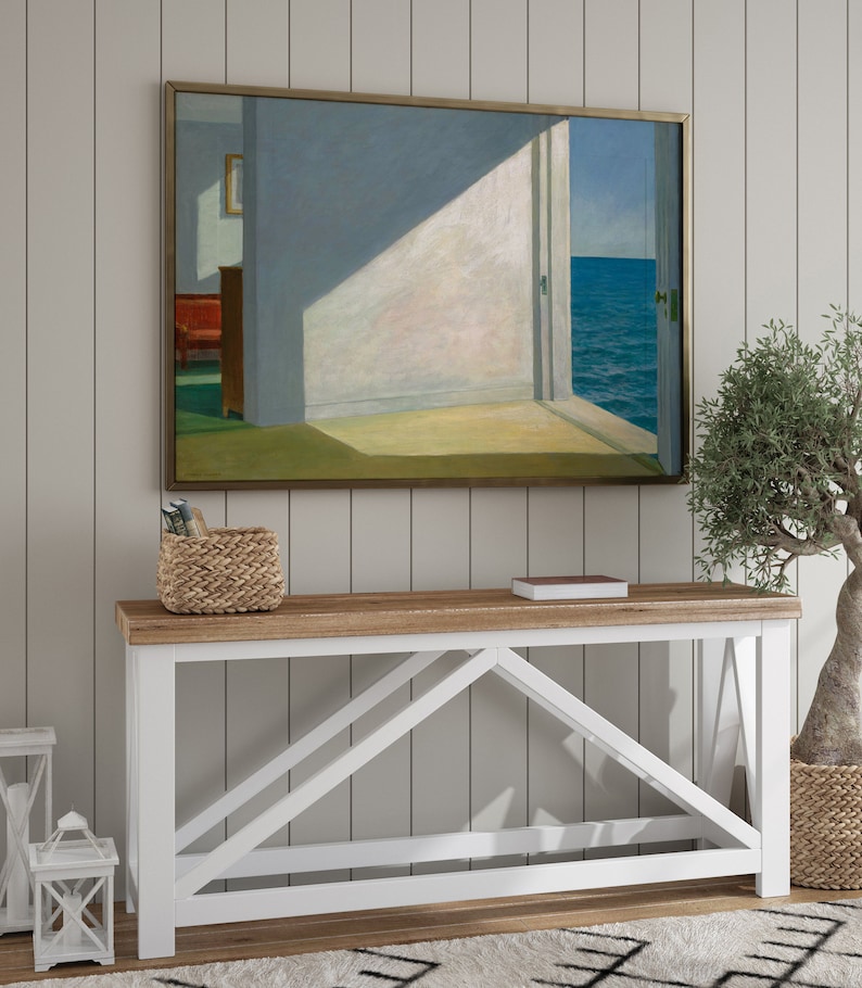 May include: A white console table with a wooden top and a farmhouse style design. The table has a simple, clean design with a wide, flat top and a sturdy base. The table is perfect for displaying decor, books, or other items.