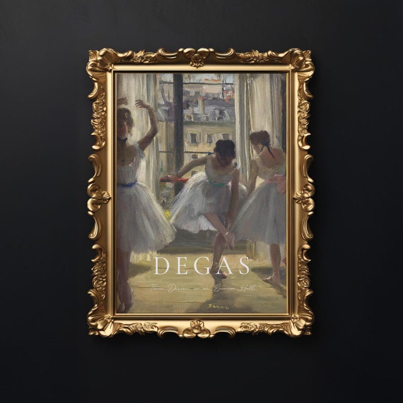 May include: A framed print of a painting by Edgar Degas depicting three ballerinas in a dance studio. The painting is in a gold frame with ornate details. The title of the painting is "Degas: The Dancers in a Rehearsal Hall" and is printed below the image.
