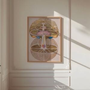 May include: A framed print of a colorful abstract design with geometric shapes and lines. The design is reminiscent of a mandala or a tree of life. The print is in a light wood frame and is hanging on a white wall.