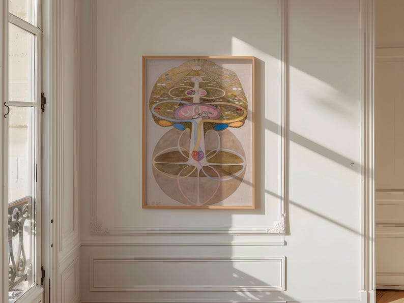 May include: A framed print of a colorful abstract design with geometric shapes and lines. The design is reminiscent of a mandala or a tree of life. The print is in a light wood frame and is hanging on a white wall.