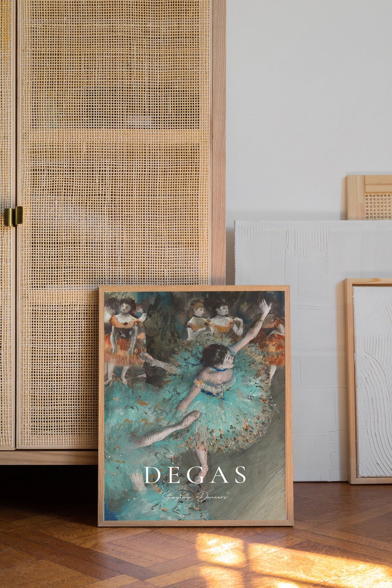 May include: A framed print of a painting by Edgar Degas depicting a group of dancers in a ballet studio. The dancers are wearing colorful tutus and are in various poses. The painting is titled "Dancing Dancers" and is signed "Degas".